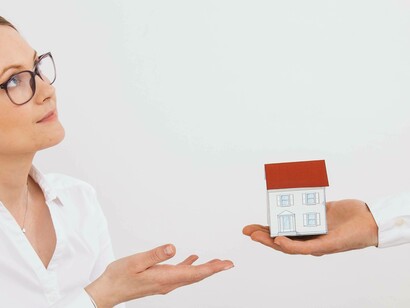 Una mano maschile offre un modellino di casa a una donna