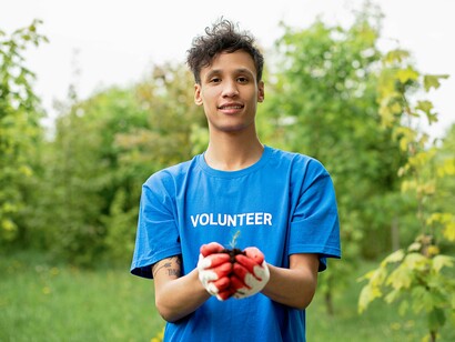 A volunteer planting a small tree during a community reforestation project, symbolizing care and renewal