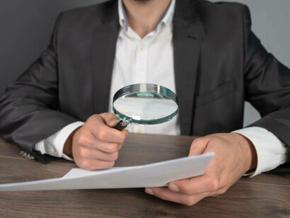 A journalist analyzing a document with a magnifying glass to ensure accurate fact-checking