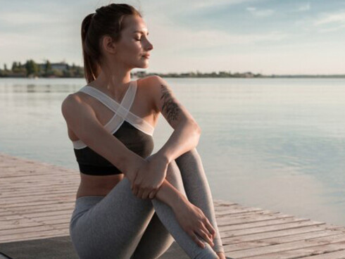 A sporty woman practices meditation exercises on the beach