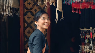 A woman standing in a fabric store, mirroring the Baduy’s devotion to handwoven textiles as carriers of ancestral meaning