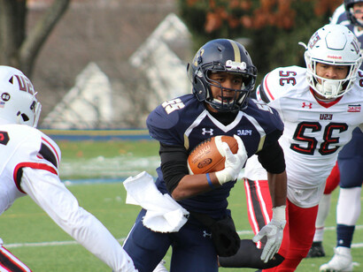 A football player running with the ball, evading tackles on the field