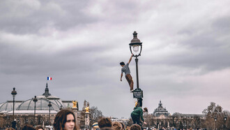 A man climbing a light tower during protests in Paris, France