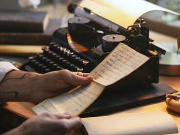 A man typing at a typewriter on his desk