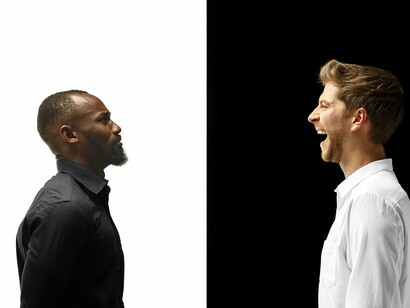 A visual clash of light and dark, one person laughing and the other frowning, illustrating how opposition is an inevitable force in human interaction that, when mediated, can lead to new understanding
