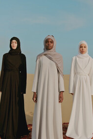 Three women stand resilient in the vast desert, embodying the spirit of Ahlam Mosteghanemi's literary exploration of identity and empowerment in the Arab world