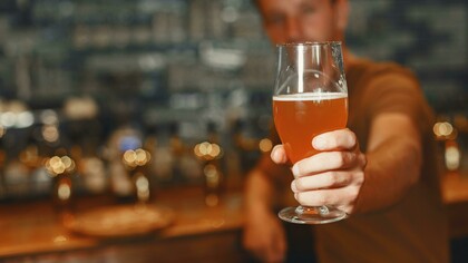 A man with a beer glass in his hand, sitting in a bar, enjoying pint of his beer