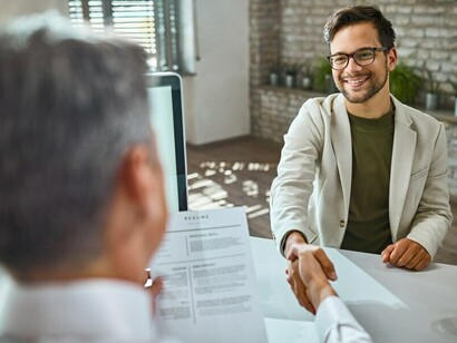 A smiling male candidate exchanging greetings with a member of the human resources team during a job interview, highlighting the employer-candidate interaction