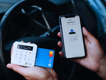 A person using a card reader and phone to complete a transaction represents how mobile money improved lives