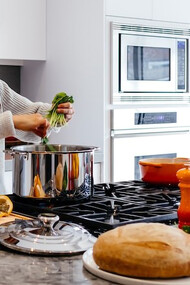 Radiate joy in the kitchen as you capture the delightful moment of a woman smiling while she prepares a meal