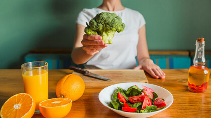 A women showcasing a variety of rich nutrient vegetables and fruits  providing a more successful cleanse