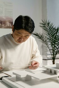 An architect refines a physical scale model, bringing traditional craftsmanship with digital design