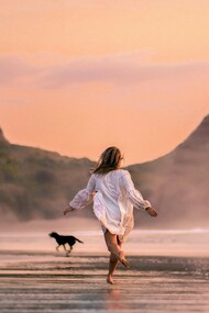 Une femme qui court sur la plage avec un chien apprécie le goût de la liberté