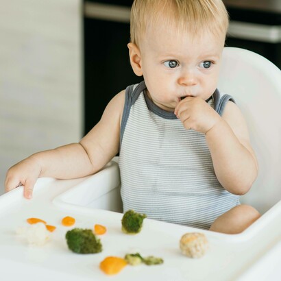 Bambino nel seggiolone che mangia le verdure: "Il sistema immunitario di un bambino è in costante evoluzione e dipende in gran parte dall’alimentazione"