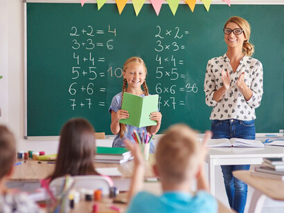 Girl student with clapping teacher in a classroom