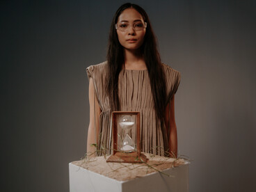 A woman behind an hourglass, mirroring the idea that aging is no longer an unstoppable countdown