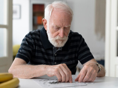 Elderly man facing Alzheimer's disease while working on a puzzle at the table