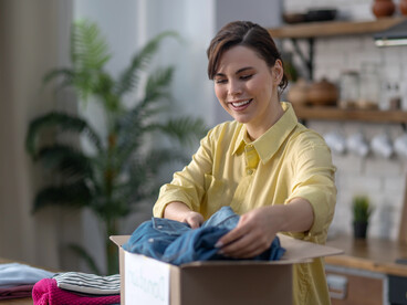 A woman, carefully packing clothes for donation as part of a wardrobe clean-out