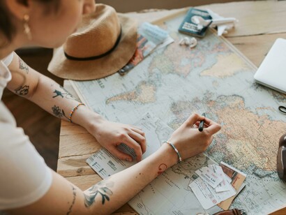Woman holding a pen, checking off destinations on a world map