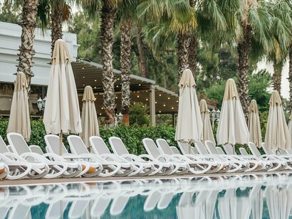 “Essa está reservada! Não viu a toalha?!”. Como se uma peça de pano ficasse subitamente investida de autoridade notarial. Mas lá está, “Se toda a gente faz, eu não vou fazer?” — é o argumento universal do conformismo