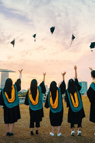 People throwing graduation hats on air