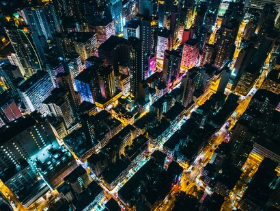 A city glowing through the night, brilliant with light, yet distant from the stars above