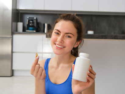 A woman holding a supplement bottle and taking a pill