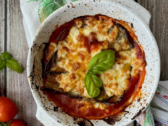 La parmigiana di melanzane nasce nel Sud Italia come piatto estivo di stratificazione, probabilmente tra Settecento e Ottocento, con origini contese e un nome ancora oggi discusso tra “parmiciana” siciliana e Parmigiano