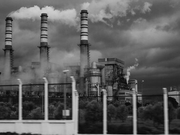 A grayscale image of smokestacks emitting carbon pollution, capturing the environmental damage caused by burning fossil fuels