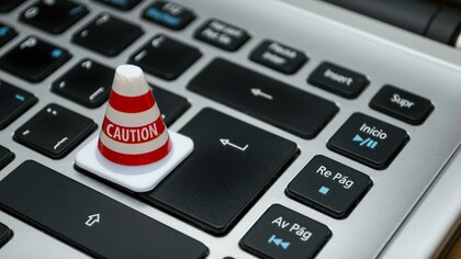 White caution cone placed on a computer keyboard symbolizing warnings about data privacy, ethical risks, and inequality in the digital world