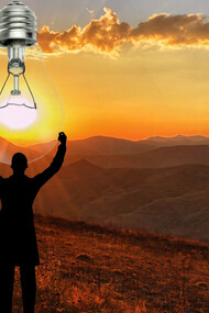 A man holds a lightbulb in the sky, powered by the sun