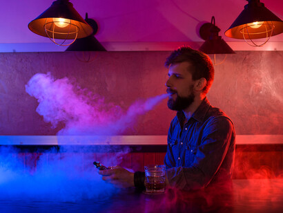A man covered in the smoke from vapes, reflecting the growing prevalence of vaping in society and the potential consequences it may have on individuals and public health 