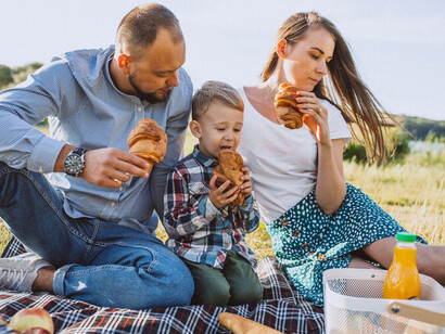 A family is enjoying a picnic in the park, happily eating pizza together