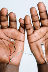 Mãos conectadas a cabos como se fossem partes de suas veias