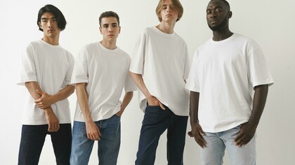 Men posing in classic white T-shirts and jeans against a minimalist backdrop