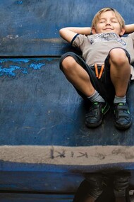 A child having what appears to be a pleasant dream as he lays in the middle of a wet road