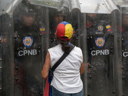 Manifestante frente a los oficiales de la Policía Nacional Bolivariana durante una protesta contra el gobierno de Maduro, marzo de 2020 en Caracas, Venezuela