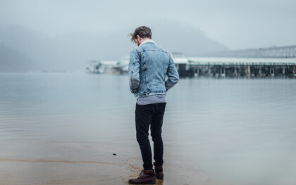 Man standing alone on the beach, looking at his reflection 