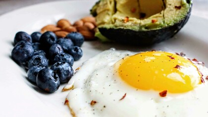 A fresh composition of an egg, blueberries, nuts, and avocado — a wholesome Paleo-inspired breakfast