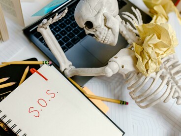 A symbolic skeleton slumped from exhaustion, illustrating how losing touch with rest drains us to the bone