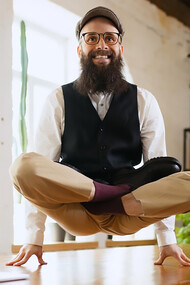 In a modern office, a smiling businessman practices relaxation techniques while sitting at his desk with his hands resting comfortably