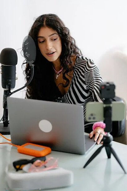 A digital content creator seated at a desk, preparing to film with her recording equipment