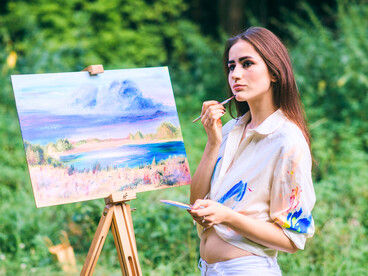 A lady creating art surrounded by nature, capturing the rebellion of existing softly yet fully