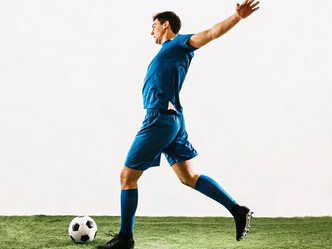 A football player running and kicking ball