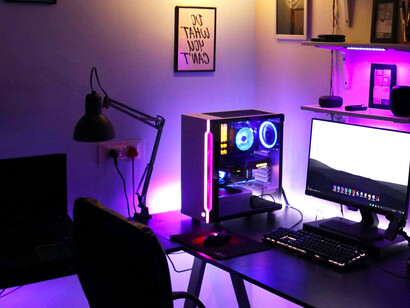 A computer workstation with headphones and a smartphone on the desk