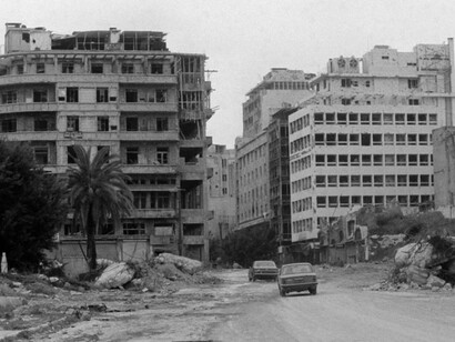 Cars pass a building destroyed by a bomb in Beirut Lebanon. Buildings across the city were targeted during the ongoing confrontation between Lebanese forces and the Palestine Liberation Organization (PLO)