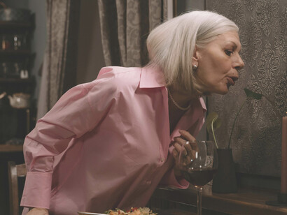 The solitary figure of a woman in pink long sleeves, dining alone in quiet reflection