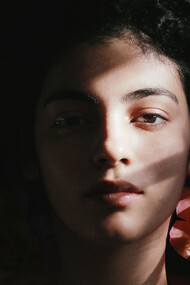 A young woman amongst flower, shadows covering one half of her face