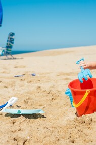 Menina brinca com areia na praia