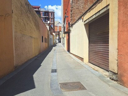 La puerta-persiana, a la derecha, era la entrada y la fachada del cobijo; la pared clara a continuación era la entrada al corral de vacas lecheras y las tres ventanas a la izquierda eran la parte de atrás de la comisaría de policía. Calle Baliarda, número 30, Barcelona, España
